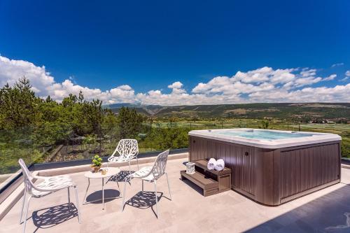 a hot tub on a patio with chairs and a table at Villa SUNRISE DREAM in Grubine