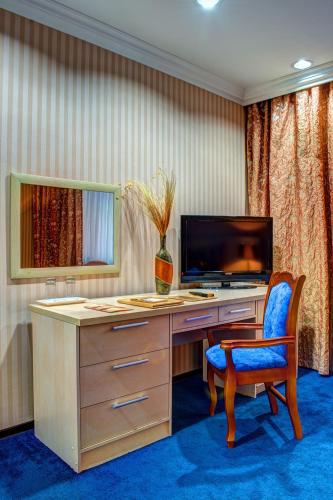 a desk with a television and a chair in a room at King Hotel Astana in Astana