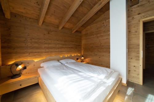 ein Schlafzimmer mit einem Bett in einer Holzwand in der Unterkunft Chalet Brisi in Wildhaus