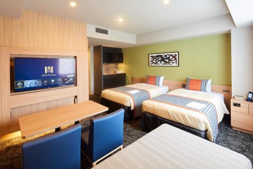 a hotel room with two beds and a flat screen tv at hotel MONday Asakusa in Tokyo