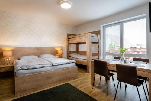 a bedroom with a bed and a desk and a table with chairs at Vila Anna - Ubytovanie Bešeňová in Bešeňová