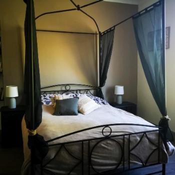 - une chambre avec un lit à baldaquin noir et des oreillers dans l'établissement Gîte à la campagne - Etat Nature, à Magnières