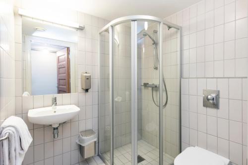 y baño con ducha y lavamanos. en Falstadsenteret - Museum, minnested og senter for menneskerettigheter en Levanger