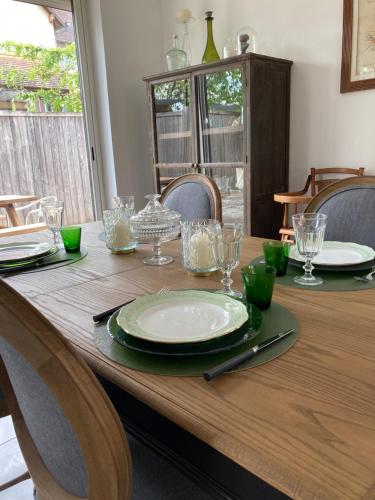 a wooden table with plates and glasses on it at La Mardelle in Saint-Gervais-la-Forêt