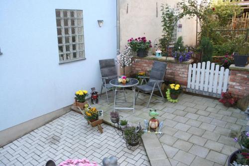 a patio with a table and chairs and flowers at Ferienwohnung Spatzennest in Edesheim in Edesheim