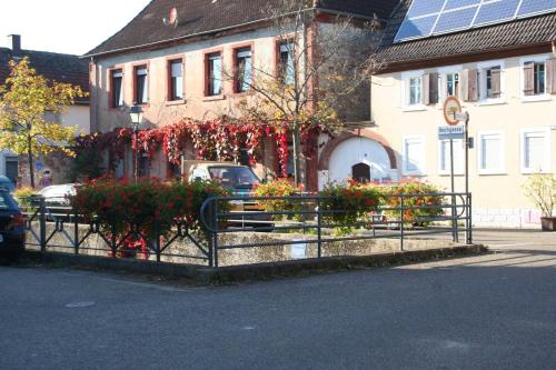 a fence with flowers in front of a building at Ferienwohnung Spatzennest in Edesheim in Edesheim