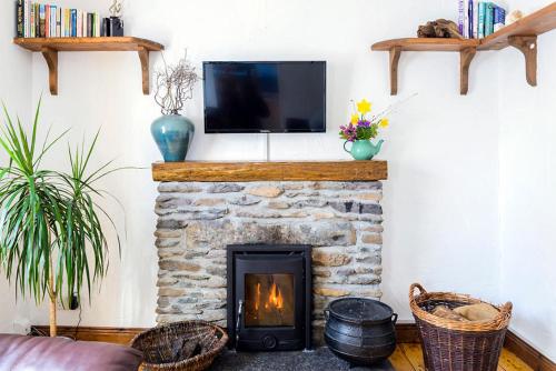 a living room with a stone fireplace with a tv at The Arch An Capall Dubh Dingle in Dingle