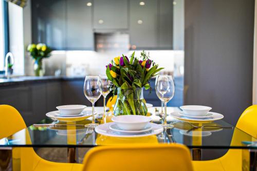 a dining table with a vase of flowers and wine glasses at Broadstairs Apartments with luxurious 4-person communal hot tub - sleeps up to 20 people in Broadstairs