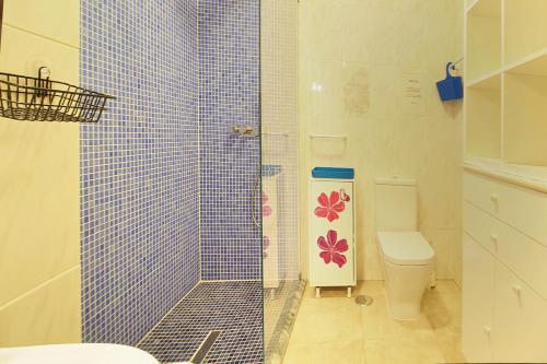La salle de bains est pourvue d'une douche carrelée de bleu et de toilettes. dans l'établissement Prestige for Home - Apt Dunamar - Praia Alagoa Altura, à Altura