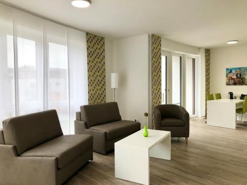 a living room with two chairs and a couch and a table at ADAPT Apartments Braunschweig in Braunschweig