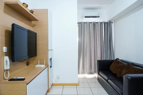 a living room with a couch and a flat screen tv at Highest Value 2BR Apartment at M-Town Residence By Travelio in Tangerang
