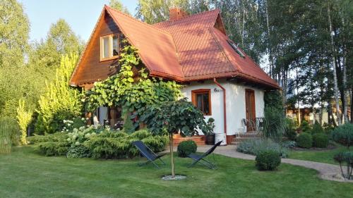 une petite maison avec deux chaises dans la cour dans l'établissement Siedlisko Gruszki Puszcza Białowieska, à Narewka