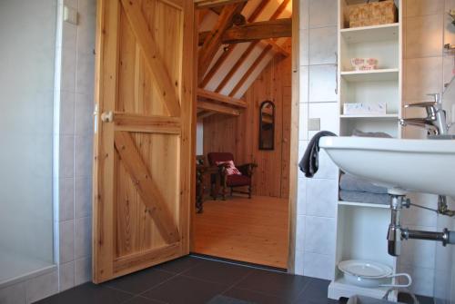 a bathroom with a wooden door and a sink at Erfgoed & Logies Den Heijkant in Moergestel