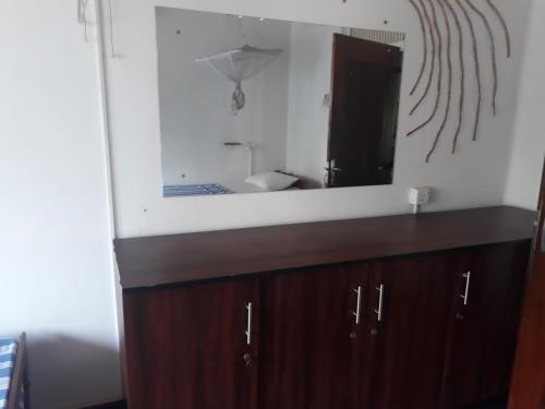 a bathroom with a mirror and a wooden cabinet at Seals Harbor Hotel in Weligama