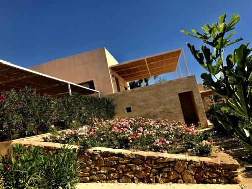 a house with a stone wall and some flowers at Case Graffeo in Menfi