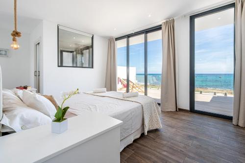 1 dormitorio con cama y vistas al océano en Tamarells A By homevillas360 en Son Serra de Marina