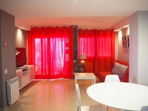 sala de estar con cortinas rojas y mesa en Apartament per 4 persones a Doctor Fleming a 5 minuts de la Platja Gran, en Platja d'Aro