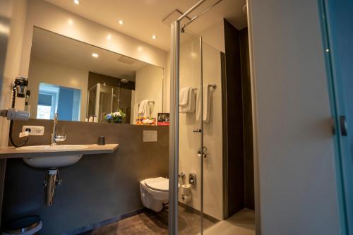 a bathroom with a toilet and a sink and a shower at Hotel Stadt Lüdenscheid in Lüdenscheid