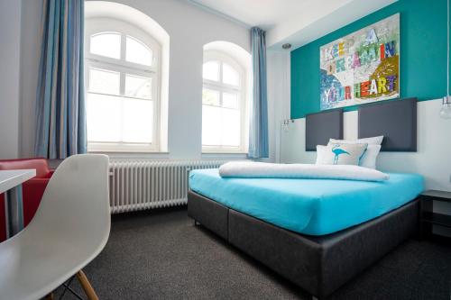 a bedroom with a blue bed and a chair at Hotel Stadt Lüdenscheid in Lüdenscheid