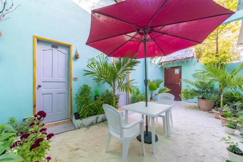 a table with a pink umbrella on a patio at Olhumathi View Inn in Ukulhas