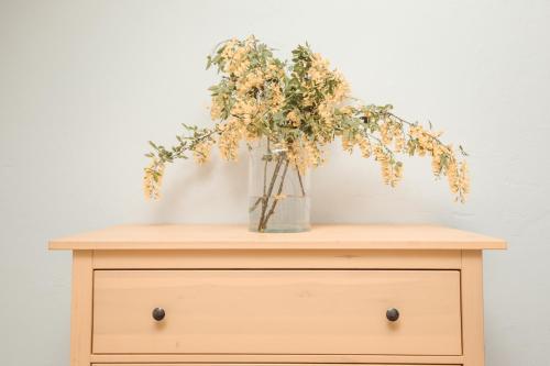 a wooden dresser with a vase of flowers on it at Tabun in Gdańsk