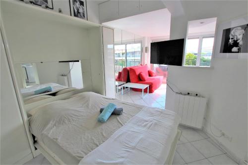 - une chambre blanche avec un lit et une chaise rouge dans l'établissement Nice apartment last floor with terrace and clear view on the sea, à Cannes