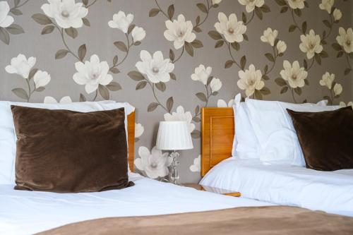 a bedroom with two beds with white flowers on the wall at The White House Inn - Whitby in Whitby
