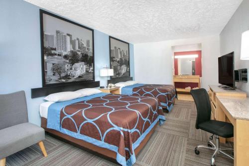 una camera d'albergo con due letti e una scrivania di Super 8 by Wyndham City of Moore a Moore