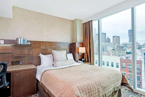 a hotel room with a bed and a large window at Wyndham Garden Chinatown in New York
