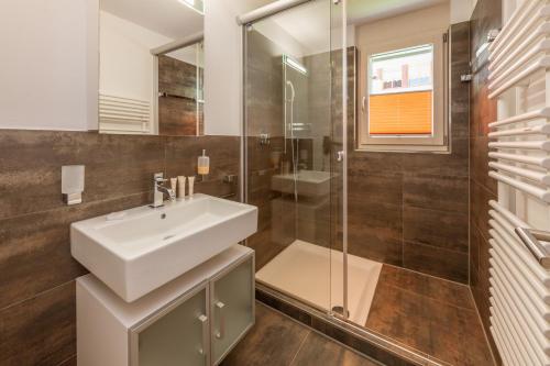 a bathroom with a sink and a glass shower at Casa Della Luce Apartments by Zermatt Premium Apartments in Zermatt