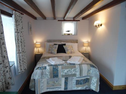 a bedroom with a bed with two lamps and a window at Brambles Cottage in Boyton