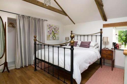 a bedroom with a black bed and a window at Red River Stables - Peaceful, beautiful grounds, swimming pool, central location for West Cornwall in Camborne