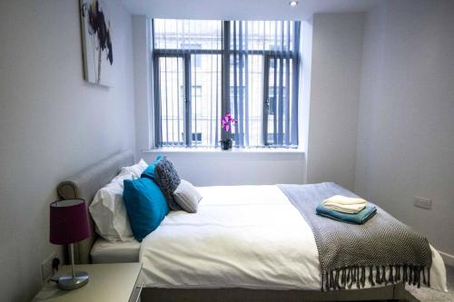 um quarto com uma cama branca e uma janela em StayZo - Executive City Centre Apartment 2 em Bradford