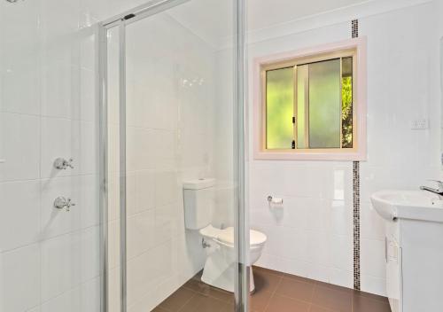 a white bathroom with a toilet and a glass shower at Econo Lodge Alabaster in Cowra