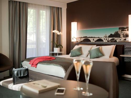 Habitación de hotel con cama y mesa con copas de vino en Mercure Pont d’Avignon Centre en Aviñón
