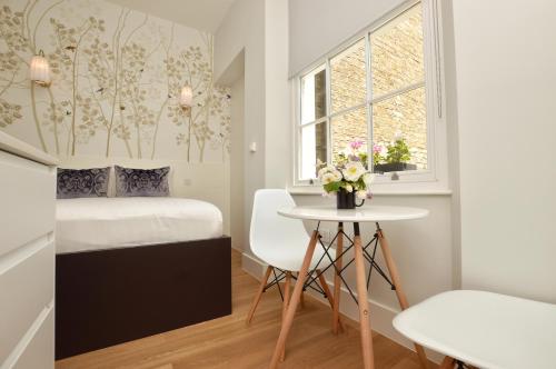 a small bedroom with a bed and a table at StayPrime Notting Hill Serviced Apartments in London