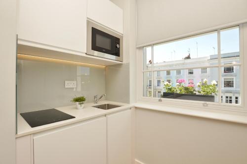 a white kitchen with a sink and a window at StayPrime Notting Hill Serviced Apartments in London