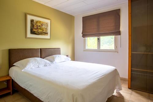 1 dormitorio con 1 cama blanca grande y ventana en Le Petit Viala, en Capestang
