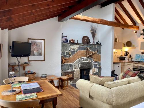 ein Wohnzimmer mit einem Steinkamin und einem Tisch in der Unterkunft Mountainstudios Beudy Bach & Beudy Mawr in Bangor