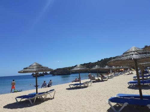 a group of beach chairs and umbrellas on a beach at VP Flat with Balcony and Pool View in Alvor
