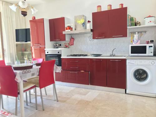 a kitchen with red cabinets and a table with red chairs at Casa Vacanze Arba Girasole in Girasole