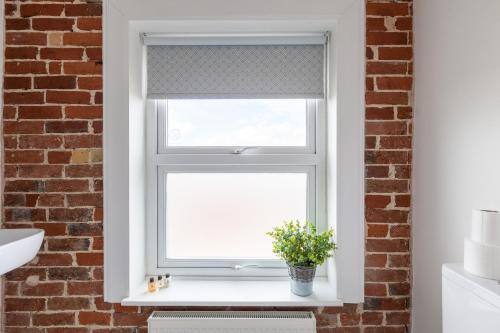 una ventana en un baño con una planta en el alféizar de la ventana en The Caledon Guest House, en Cowes