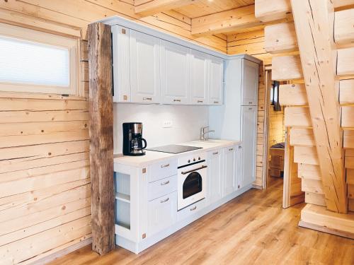 eine Küche mit weißen Schränken in einem Blockhaus in der Unterkunft Log House Natura in Radovljica