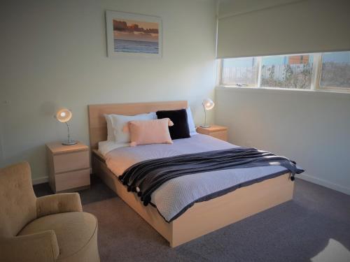 a bedroom with a bed with two lamps and a chair at Port Central No 4 in Port Campbell