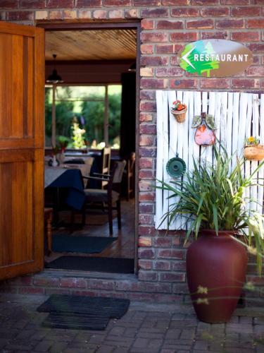 a door to a restaurant with a plant in a vase at Andelomi Forest Lodge in Stormsrivier