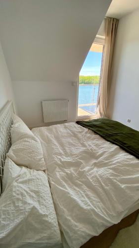 a white bed in a room with a window at Apartament Blisko Natury in Tomaszkowo