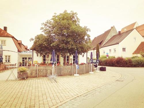 einen Innenhof mit Sonnenschirmen, Stühlen und einem Zaun in der Unterkunft Gästehaus Reisinger in Straubing