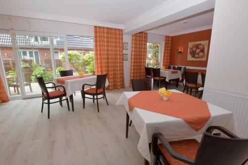 a restaurant with two tables and chairs and windows at Hotel-Pension Achtern Diek in Büsum