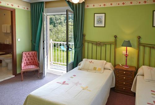 a bedroom with a bed and a chair and a window at Casa Manoli Luarca in Almuña