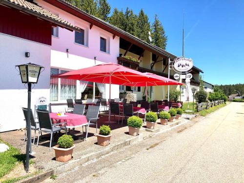 ein Restaurant mit Tischen, Stühlen und roten Sonnenschirmen in der Unterkunft Hotel Charlott in Eisenbach